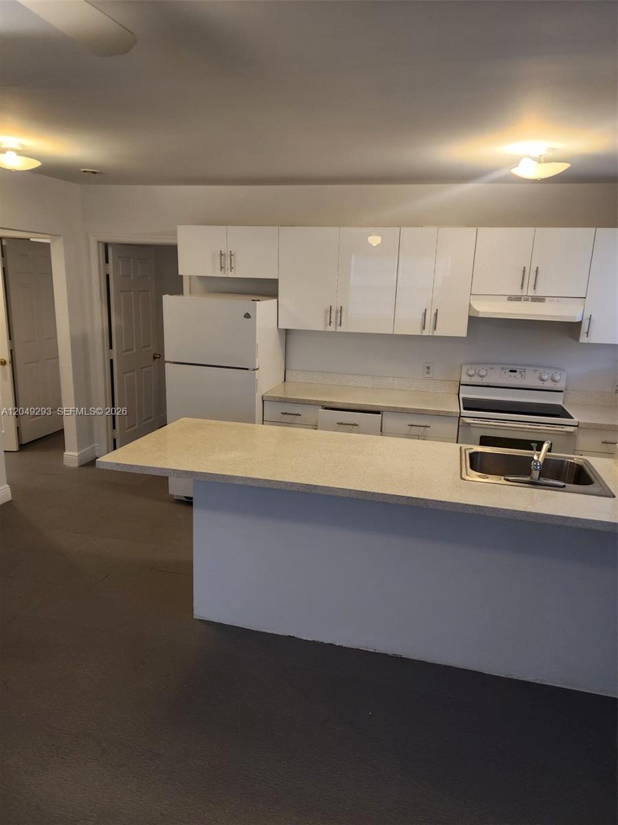 A kitchen features white flat-panel cabinets, a white refrigerator, a stove, and a breakfast bar — 14240 NW 22nd Ave # 3, Opa-Locka FL 33054, OPA-LOCKA, FL
