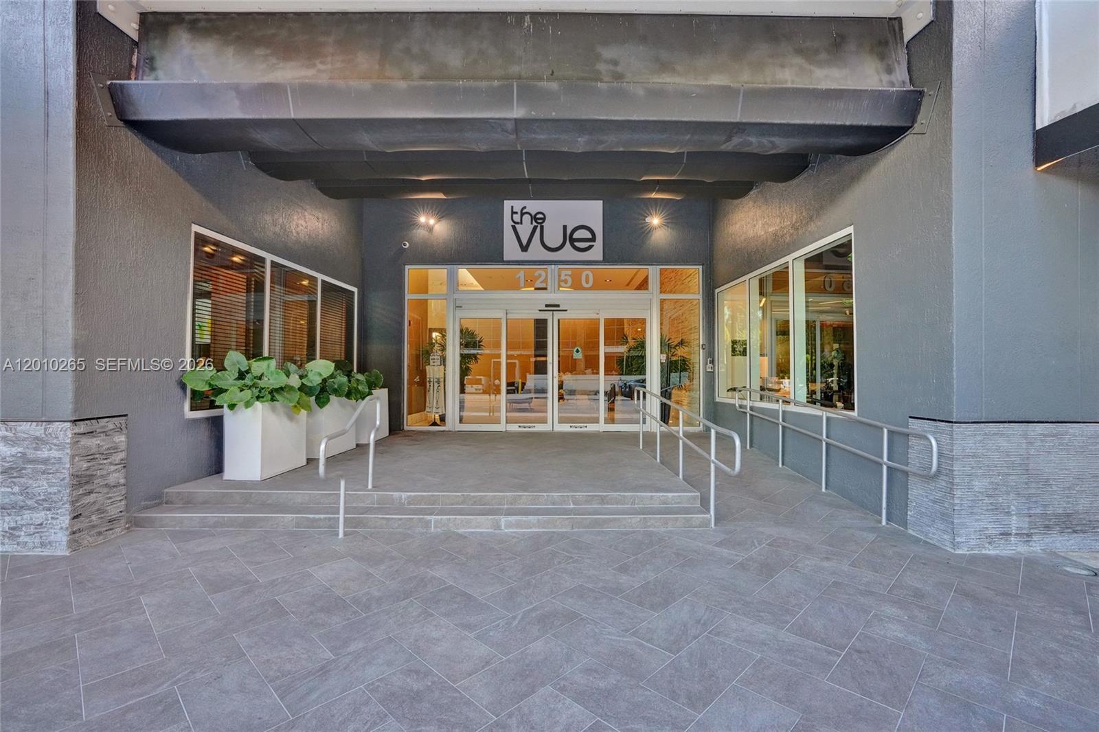 The exterior entrance of a building features a glass door, concrete steps, and metal railings — 1250 S Miami Ave # 2103, Miami FL 33130, MIAMI, FL