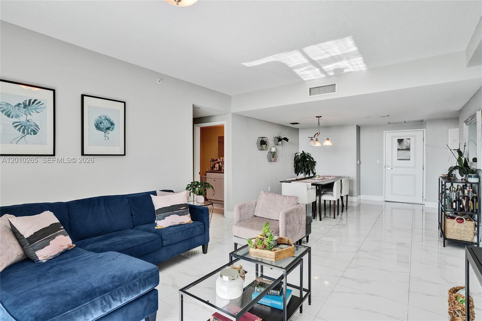 A living and dining area features a blue sectional sofa, glass coffee table, and tile flooring — 1250 S Miami Ave # 2103, Miami FL 33130, MIAMI, FL