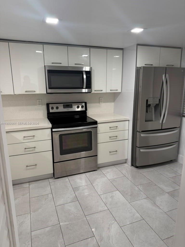 A kitchen features white cabinets, stainless steel appliances, and light-colored tile flooring — 10000 NW 9th St Cir # 11, Miami FL 33172, MIAMI, FL