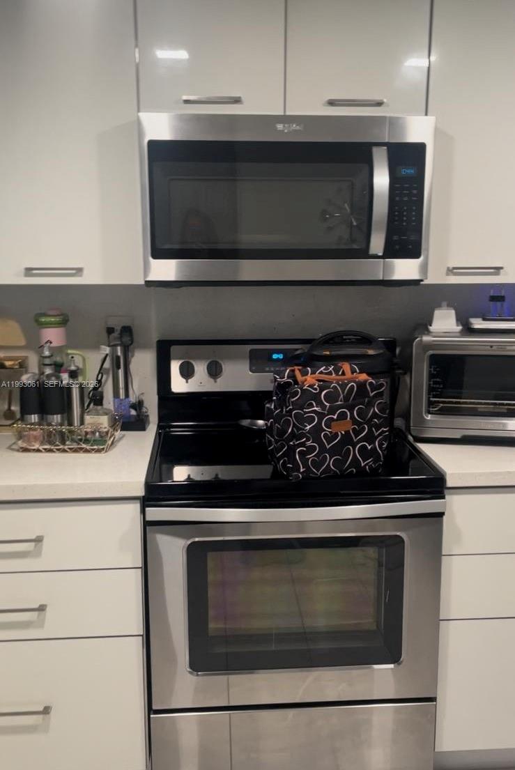 A kitchen features white cabinets, stainless steel appliances, and a black electric stove — 10000 NW 9th St Cir # 11, Miami FL 33172, MIAMI, FL