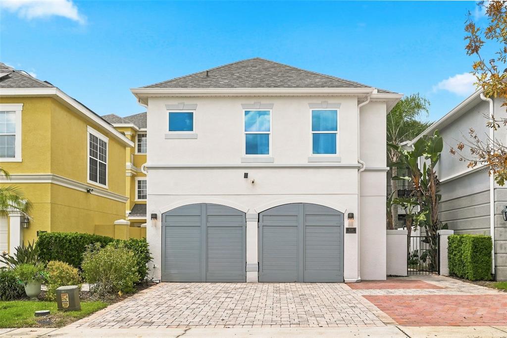 A two-story house with a white stucco exterior and two gray arched garage doors — 1530 COROLLA COURT, REUNION, FL