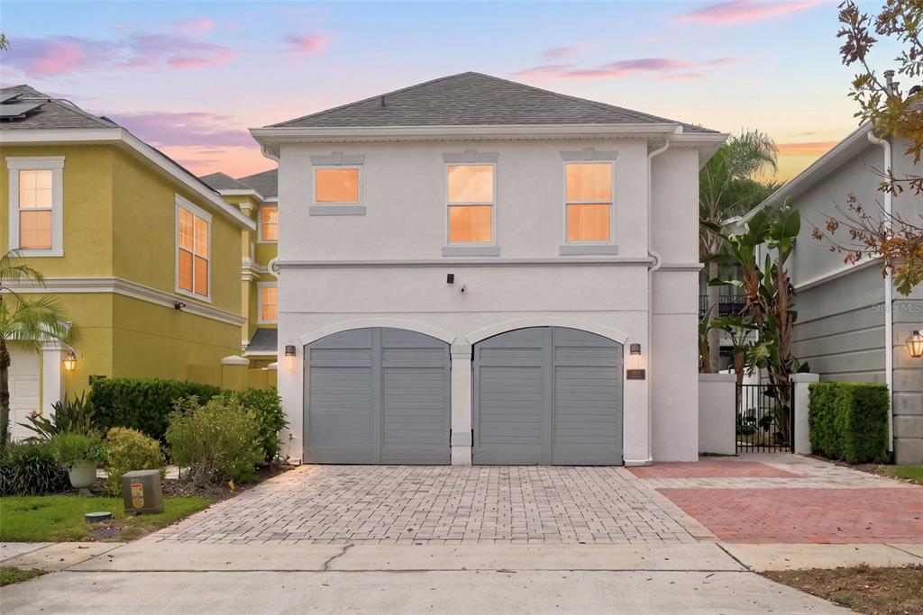 A two-story house with a white stucco exterior and two gray arched garage doors — 1530 COROLLA COURT, REUNION, FL