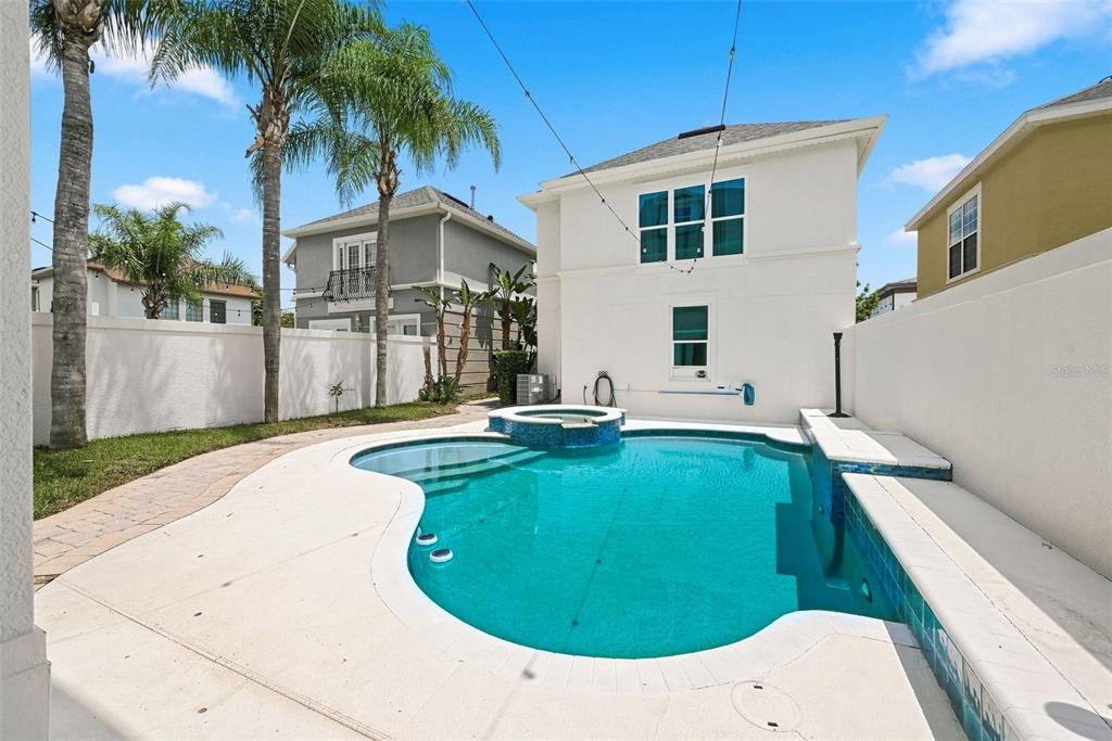 A backyard features a swimming pool with an attached spa and a white privacy wall — 1530 COROLLA COURT, REUNION, FL