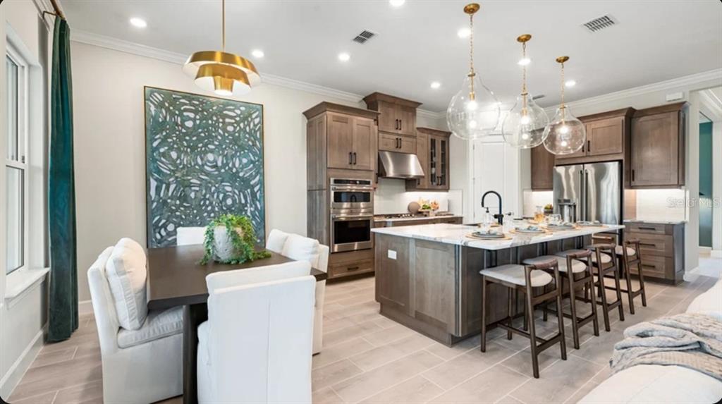 A kitchen and dining area with wood cabinets, a marble island, and pendant lighting — 7636 MOONBEAM AVENUE, SARASOTA, FL