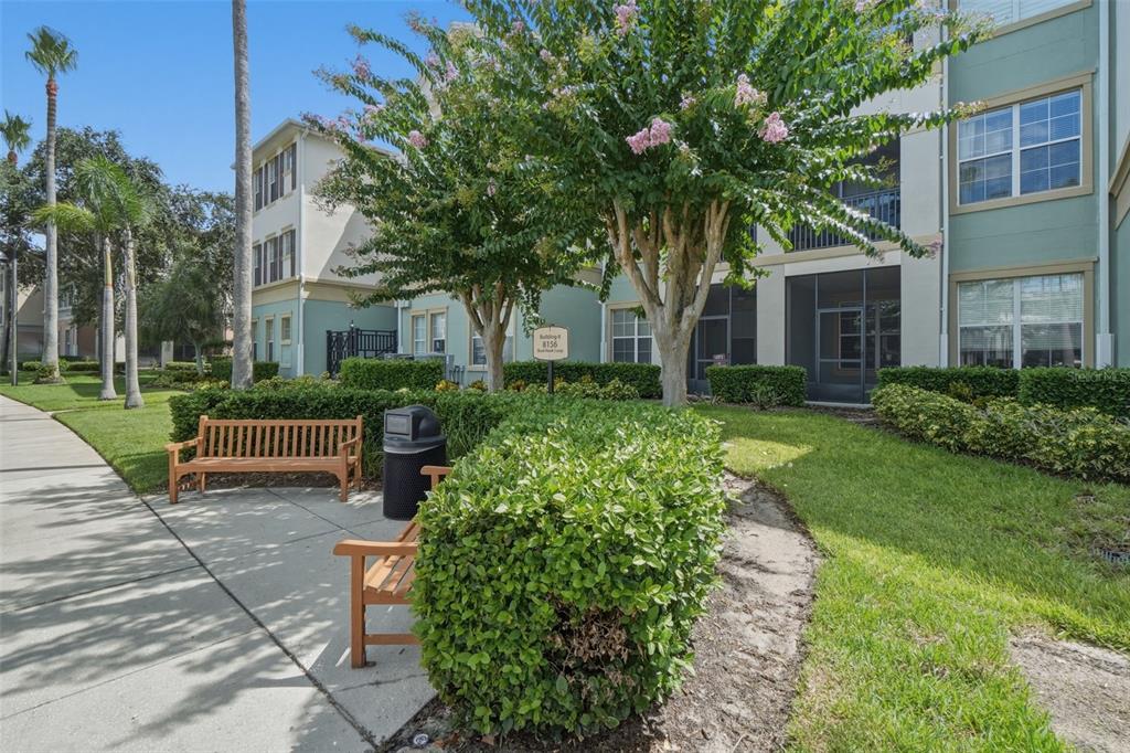 A wooden bench sits on a sidewalk in front of a multi-story apartment building — 8156 BOAT HOOK LOOP UNIT 109, WINDERMERE, FL