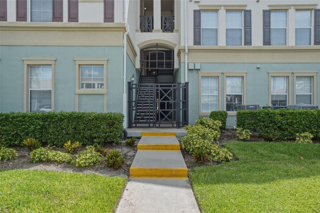 A concrete walkway leads to a gated entrance of a multi-story apartment building — 8156 BOAT HOOK LOOP UNIT 109, WINDERMERE, FL