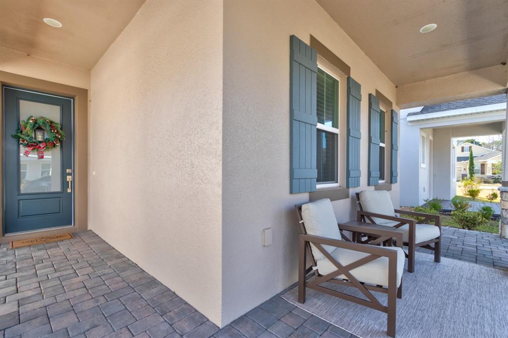 A covered front porch features a dark door, two chairs, and blue shutters on windows — 828 MIDDLETON STREET, DEBARY, FL