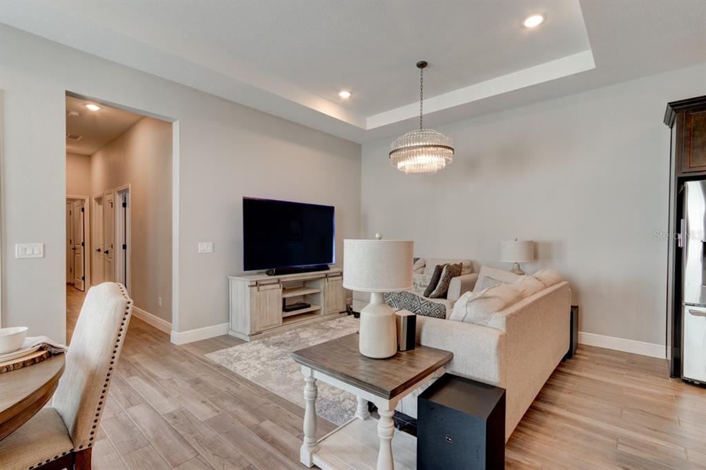 A living room features a tray ceiling, a crystal chandelier, and light wood-look flooring — 828 MIDDLETON STREET, DEBARY, FL