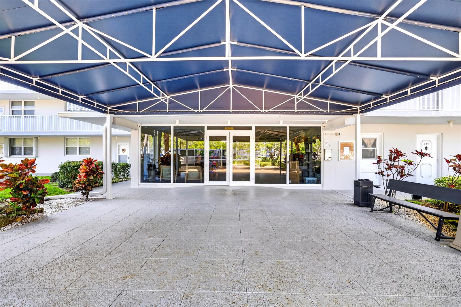 A covered entryway features a blue awning over a tiled patio with a bench — 5961 NW 2nd Avenue # 302, Boca Raton FL 33487, BOCA RATON, FL