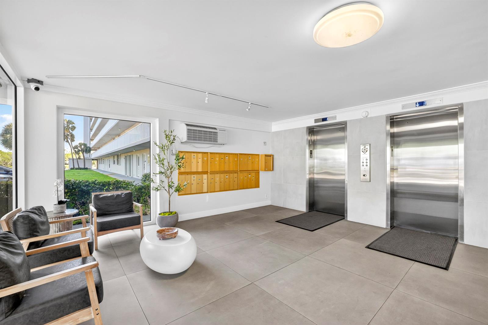 A modern lobby features gray tile floors, two stainless steel elevators, and a wall of mailboxes — 5961 NW 2nd Avenue # 302, Boca Raton FL 33487, BOCA RATON, FL