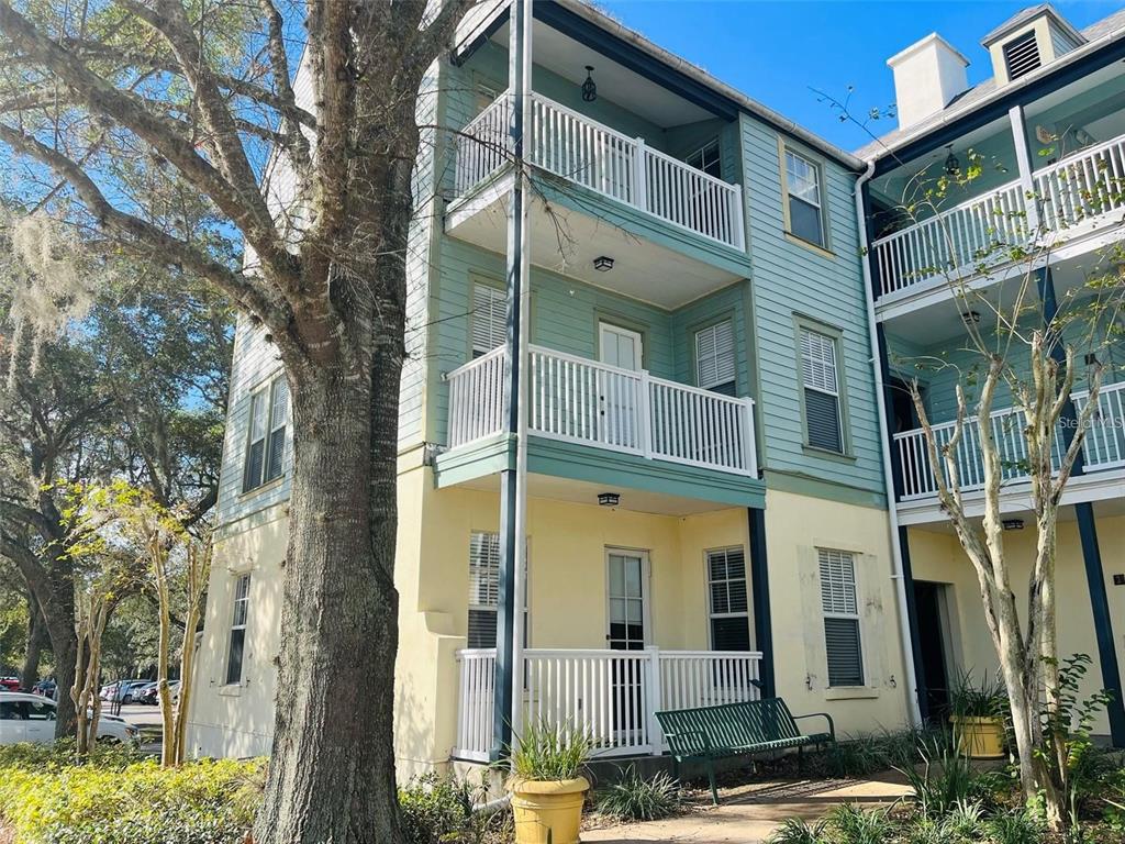 A three-story building with light green and yellow siding features stacked balconies and white railings — 611 CAMPUS STREET UNIT 180, CELEBRATION, FL
