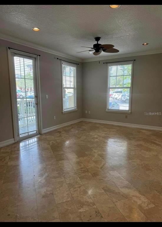 An empty room features light-colored stone tile flooring, a ceiling fan, and two windows — 611 CAMPUS STREET UNIT 180, CELEBRATION, FL