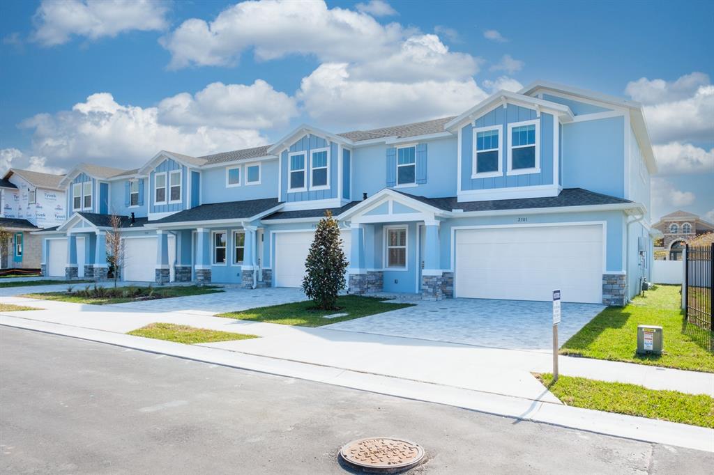 A row of light blue two-story townhomes with white garage doors and stone accents — 2500 MARIO WAY, CLEARWATER, FL