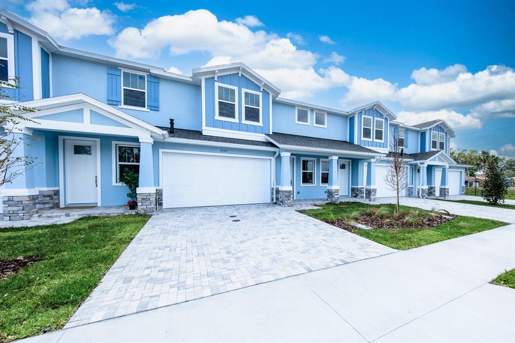 A row of light blue townhomes with white trim, stone accents, and paved driveways — 2500 MARIO WAY, CLEARWATER, FL