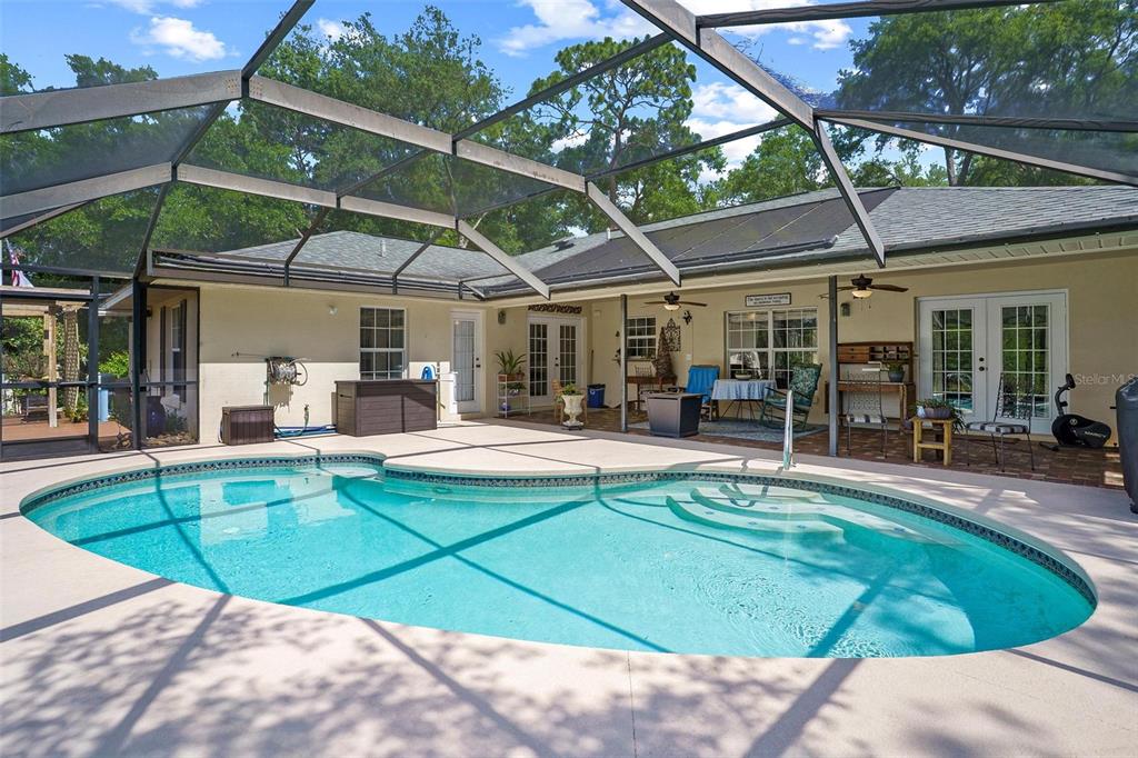 A screened-in patio features a swimming pool with steps and a covered outdoor seating area — 4024 EAGLE RIDGE ROAD, FRUITLAND PARK, FL