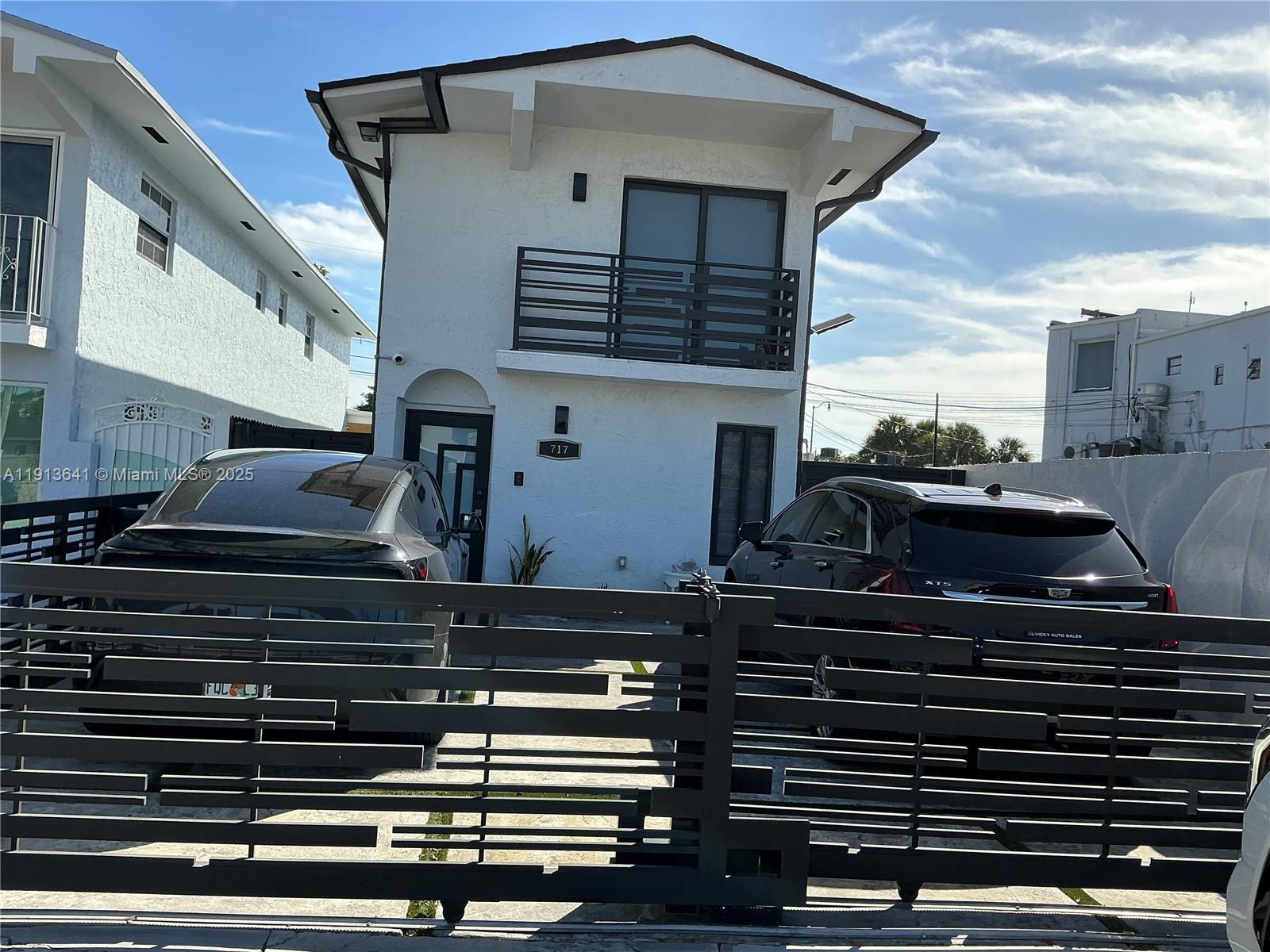 A two-story white house with a balcony and a gated driveway sits between two buildings — 717 Tamiami Canal Rd, Miami FL 33144, MIAMI, FL