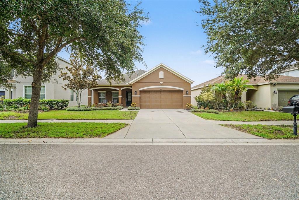 An open-concept kitchen with granite countertops and wood cabinets overlooks a dining and living area — 2722 WINGLEWOOD CIRCLE, LUTZ, FL
