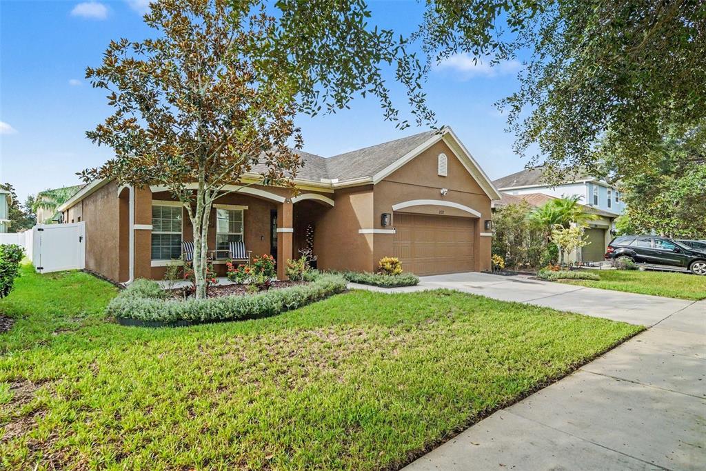 An open-concept living room and kitchen featuring tile flooring, a white sofa, and wood cabinetry — 2722 WINGLEWOOD CIRCLE, LUTZ, FL