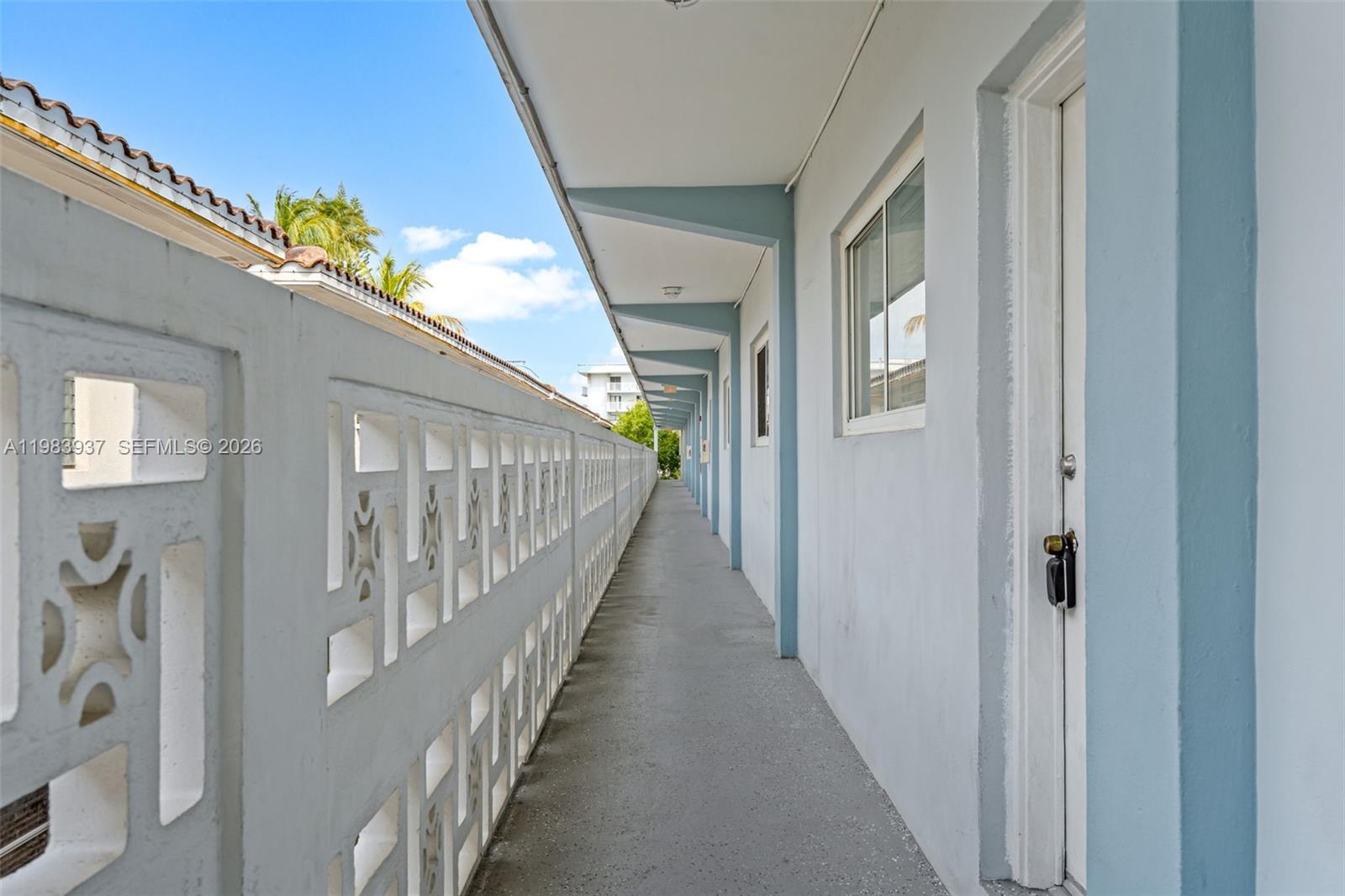 An outdoor walkway features a decorative concrete block railing and a row of unit doors — 1185 Marseille Dr # 202, Miami Beach FL 33141, MIAMI BEACH, FL