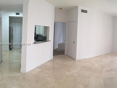An interior view showing a tiled living area with a kitchen pass-through and hallway access — 888 Brickell Key Dr # 600, Miami FL 33131, MIAMI, FL