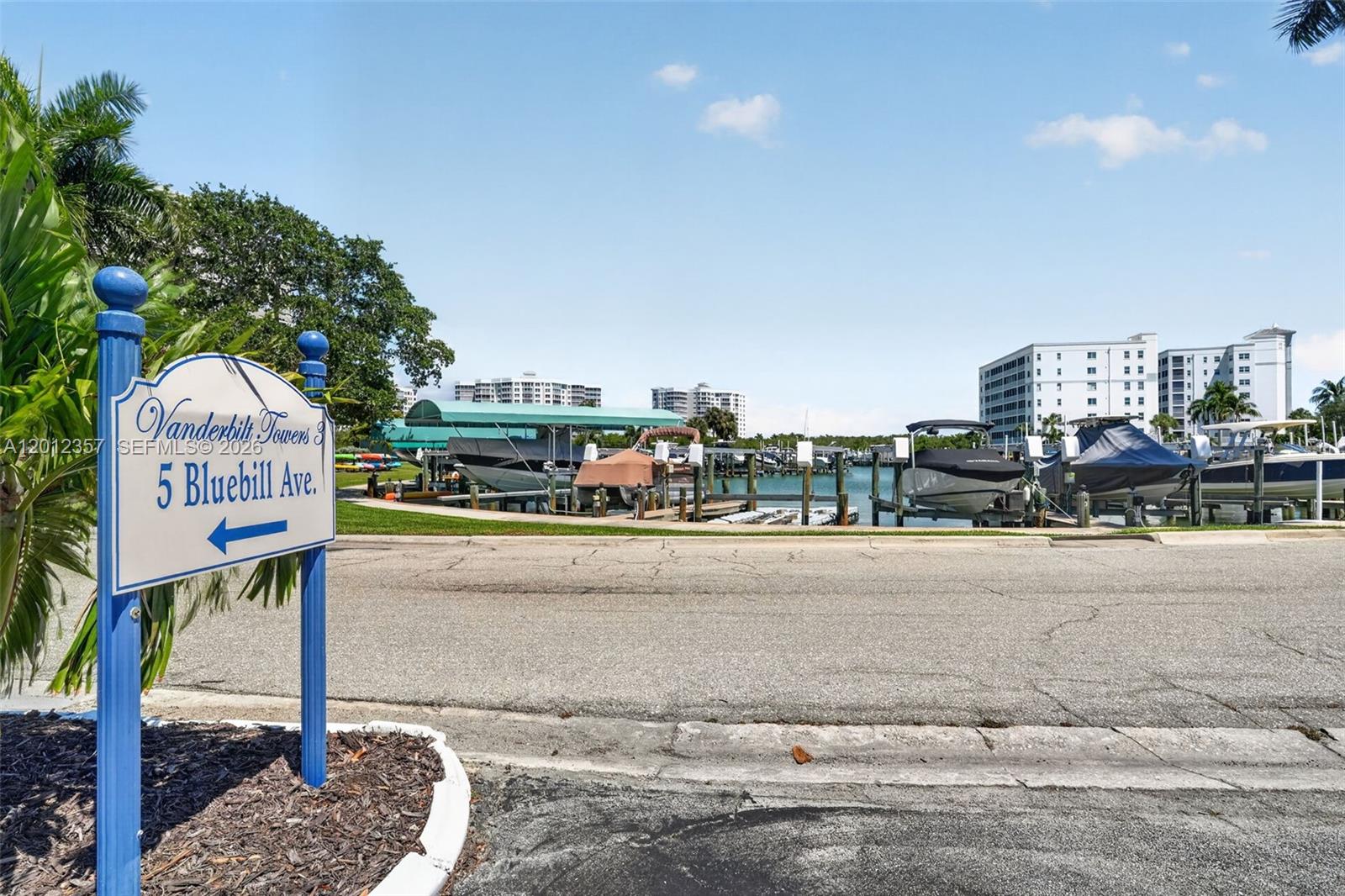 A sign points toward a marina with docked boats and multi-story buildings in the background — 5 Bluebill # 201, Naples FL 34108, NAPLES, FL