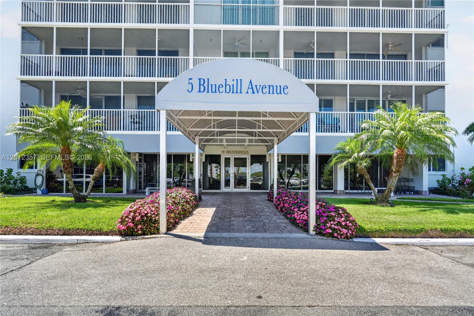 The exterior of a multi-story residential building features a covered entrance with a prominent awning — 5 Bluebill # 201, Naples FL 34108, NAPLES, FL