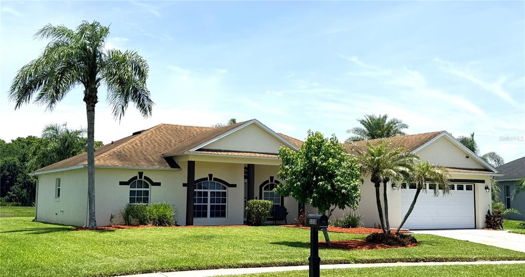 A single-story house with a white stucco exterior, a two-car garage, and palm trees — 3338 GATOR BAY CREEK BOULEVARD, ST CLOUD, FL