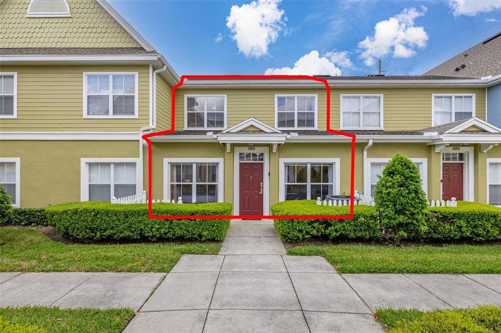 The exterior of a two-story townhouse with green siding, a red front door, and landscaping — 2250 SAN VITAL DRIVE UNIT 105, KISSIMMEE, FL