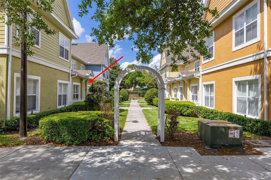 A red arrow points to a townhouse exterior with green siding and a white fence — 2250 SAN VITAL DRIVE UNIT 105, KISSIMMEE, FL