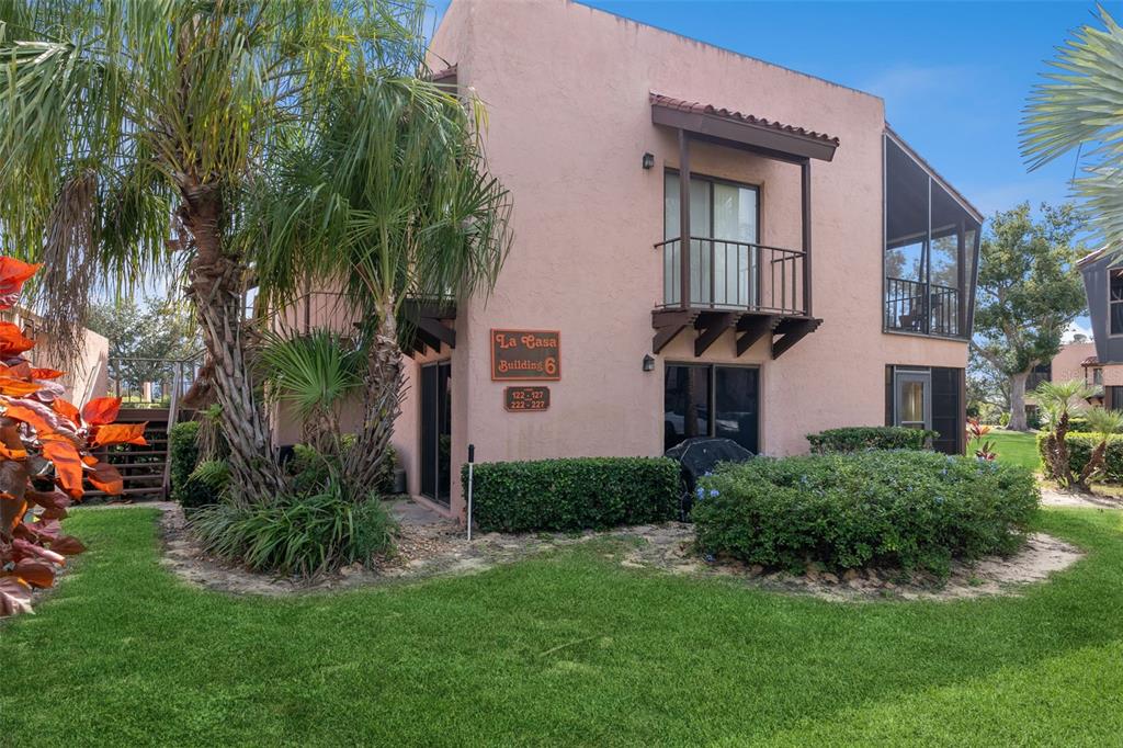 A two-story pink stucco apartment building with a balcony and surrounding landscaping — 127 LA CASA UNIT 6, LAKE WALES, FL