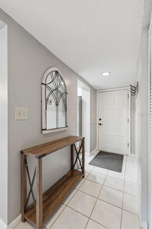 An entryway features a wood console table, an arched wall mirror, and tiled flooring — 127 LA CASA UNIT 6, LAKE WALES, FL