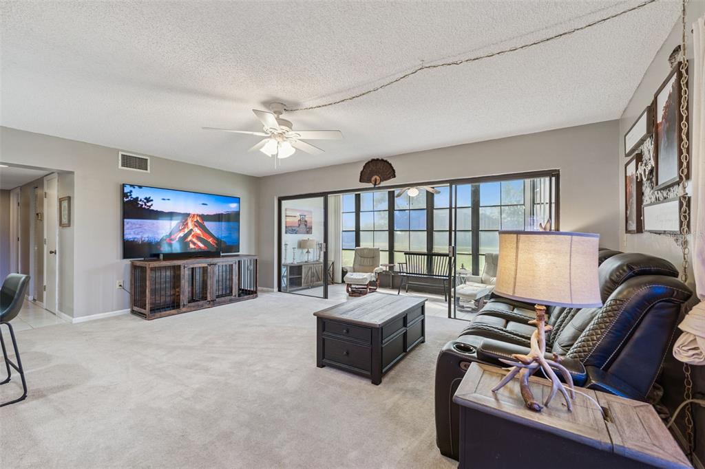 A living room features a large television, a leather sofa, and sliding glass doors — 127 LA CASA UNIT 6, LAKE WALES, FL