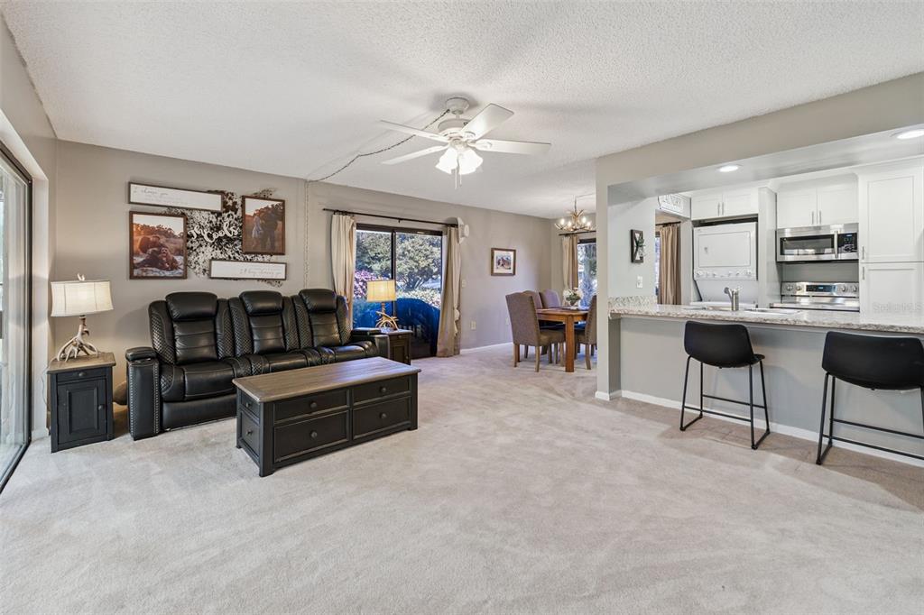 A living room with a black leather sofa, coffee table, and an open kitchen area — 127 LA CASA UNIT 6, LAKE WALES, FL