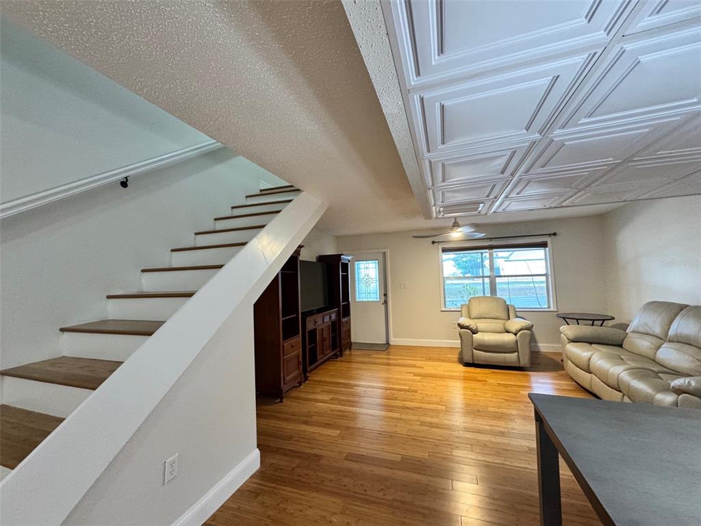 A living room features hardwood floors, a staircase, a coffered ceiling, and a leather sofa — 3255 RAMBLEWOOD PLACE, SARASOTA, FL
