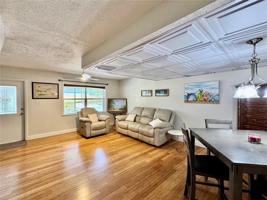 A living and dining area features hardwood floors, a coffered ceiling, and a beige sofa — 3255 RAMBLEWOOD PLACE, SARASOTA, FL