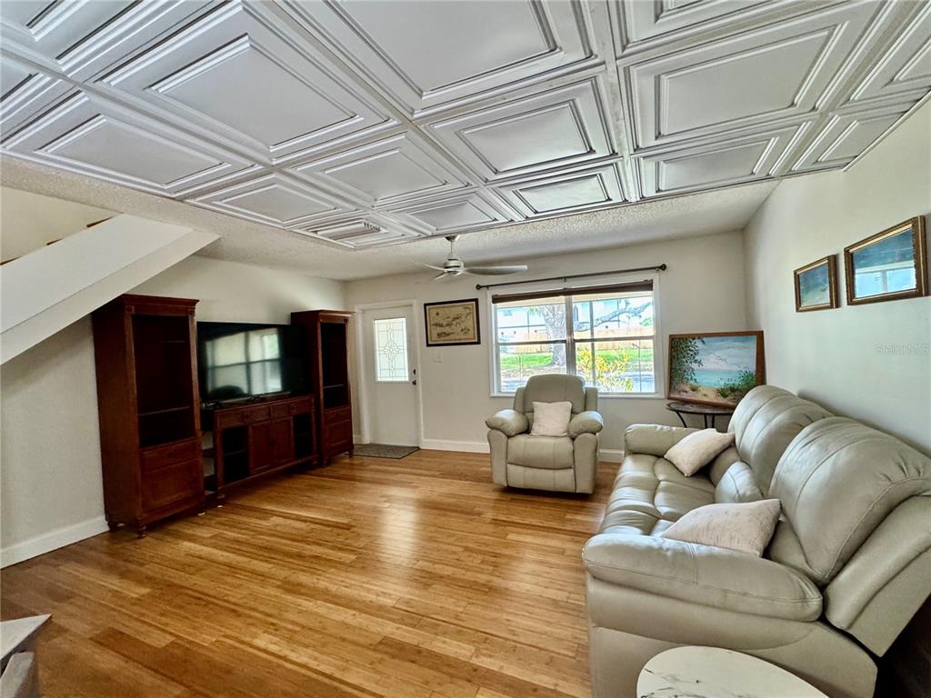 A living room features wood flooring, a coffered ceiling, a television console, and leather furniture — 3255 RAMBLEWOOD PLACE, SARASOTA, FL