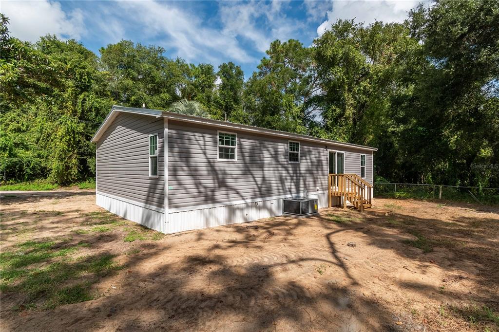 A gray manufactured home with a wooden deck and an air conditioning unit outside — 1143 SE 159TH COURT, SILVER SPRINGS, FL