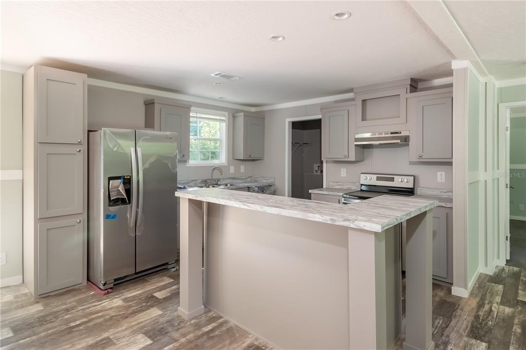 A kitchen with gray cabinets, stainless steel appliances, and a marble-patterned breakfast bar island — 1143 SE 159TH COURT, SILVER SPRINGS, FL