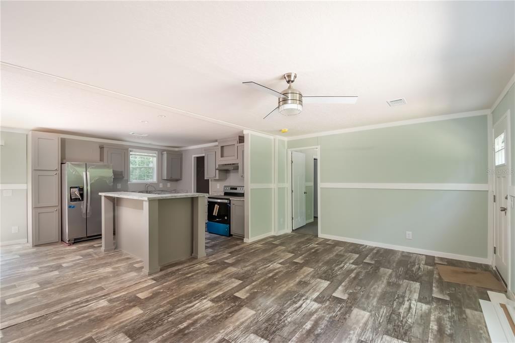 A kitchen and living area with light green walls, gray cabinets, and wood-look flooring — 1143 SE 159TH COURT, SILVER SPRINGS, FL