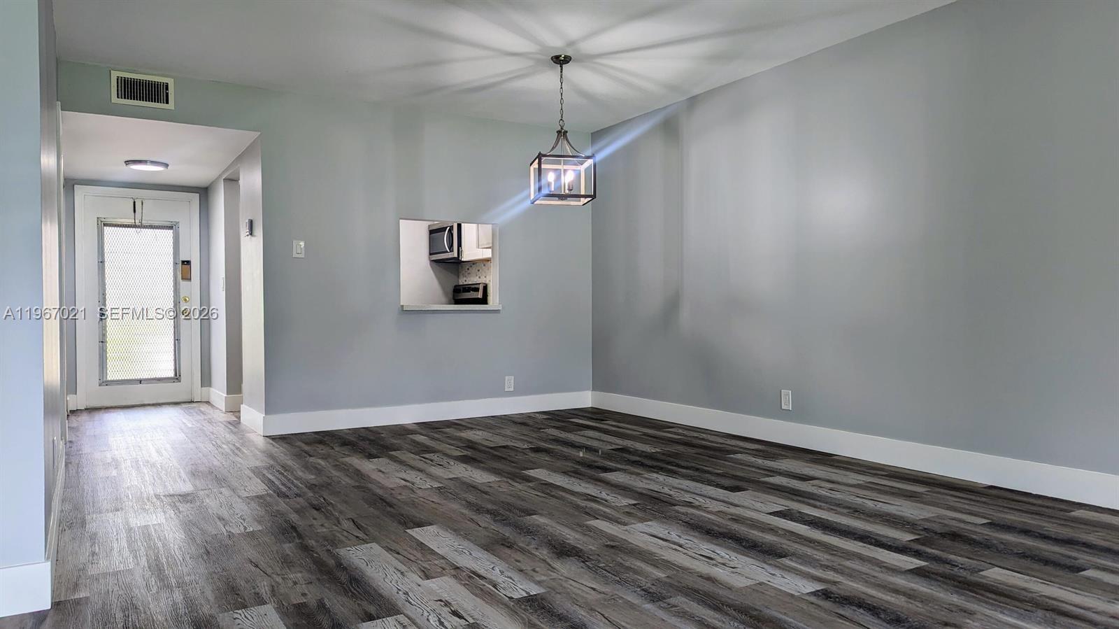 An empty room features gray walls, wood-look flooring, and a sliding glass door to a patio — 7600 NW 5th Pl # 108, Margate FL 33063, MARGATE, FL