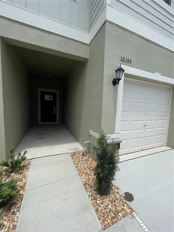 A concrete walkway leads to a recessed front door next to a single-car garage — 10199 TRUMPET HONEYSUCKLE WAY, SAN ANTONIO, FL