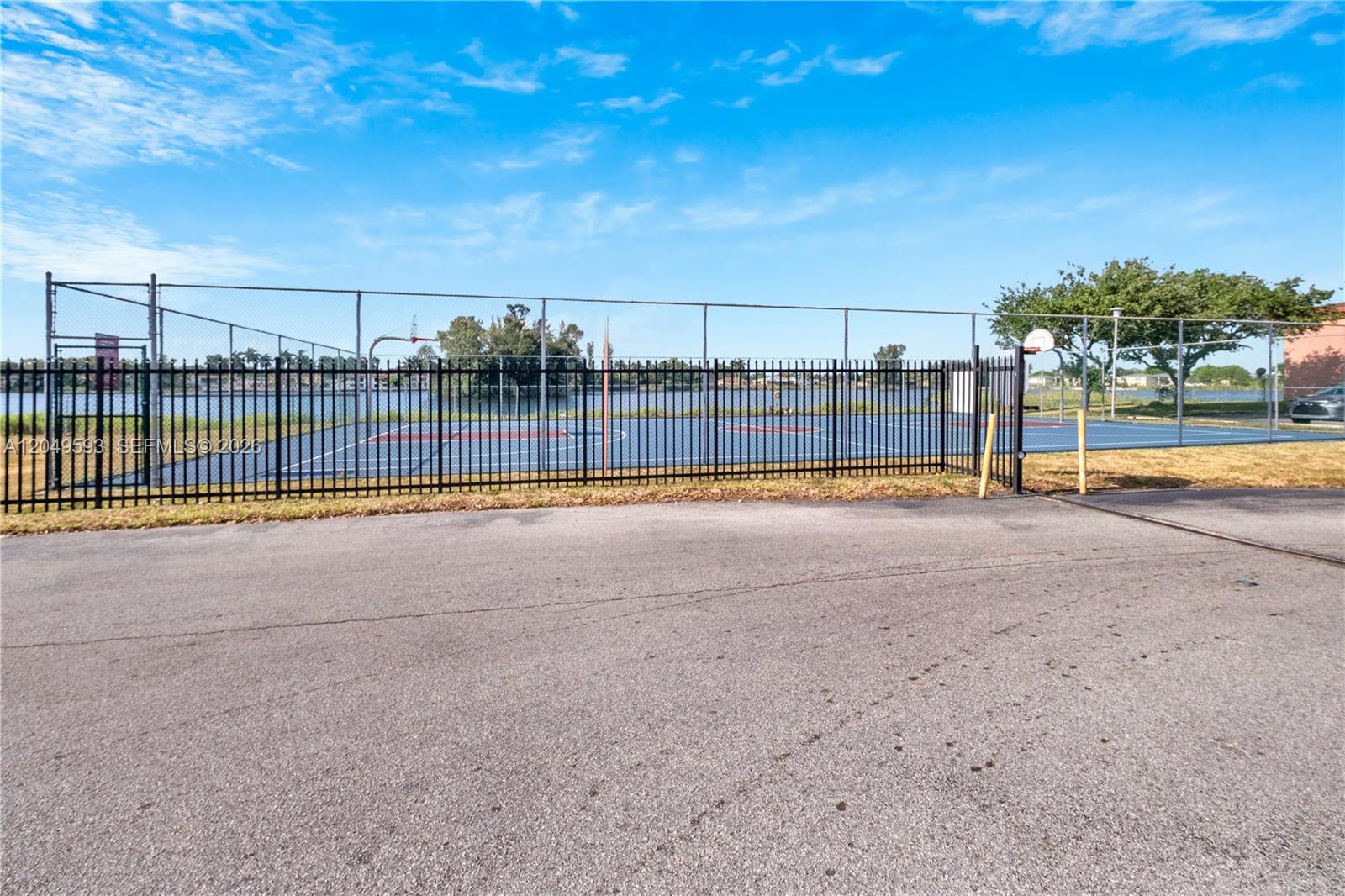 A fenced outdoor basketball court sits next to a lake under a blue sky — 2020 NW 119th St # 1122, Miami FL 33167, MIAMI, FL