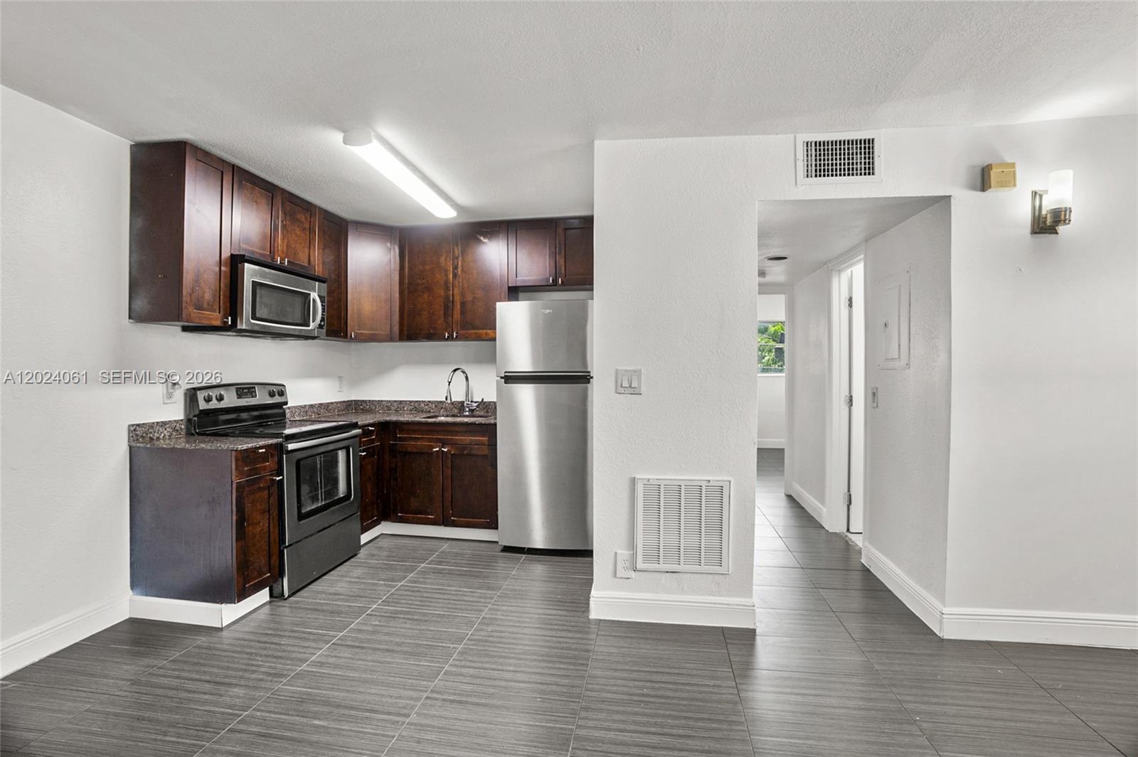 A kitchen features dark wood cabinets, stainless steel appliances, and gray tile flooring — 37 SW 14th St # 16, Dania Beach FL 33004, DANIA BEACH, FL