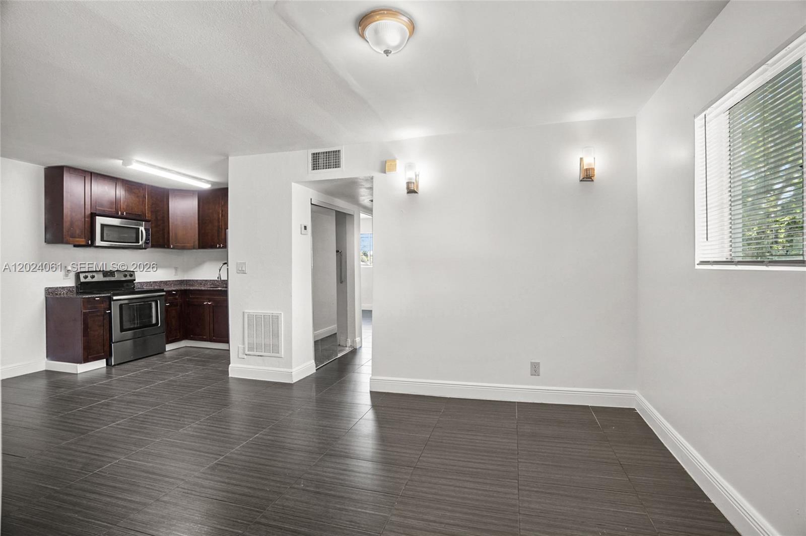 A kitchen with dark wood cabinets and tile floors opens into a dining area — 37 SW 14th St # 16, Dania Beach FL 33004, DANIA BEACH, FL