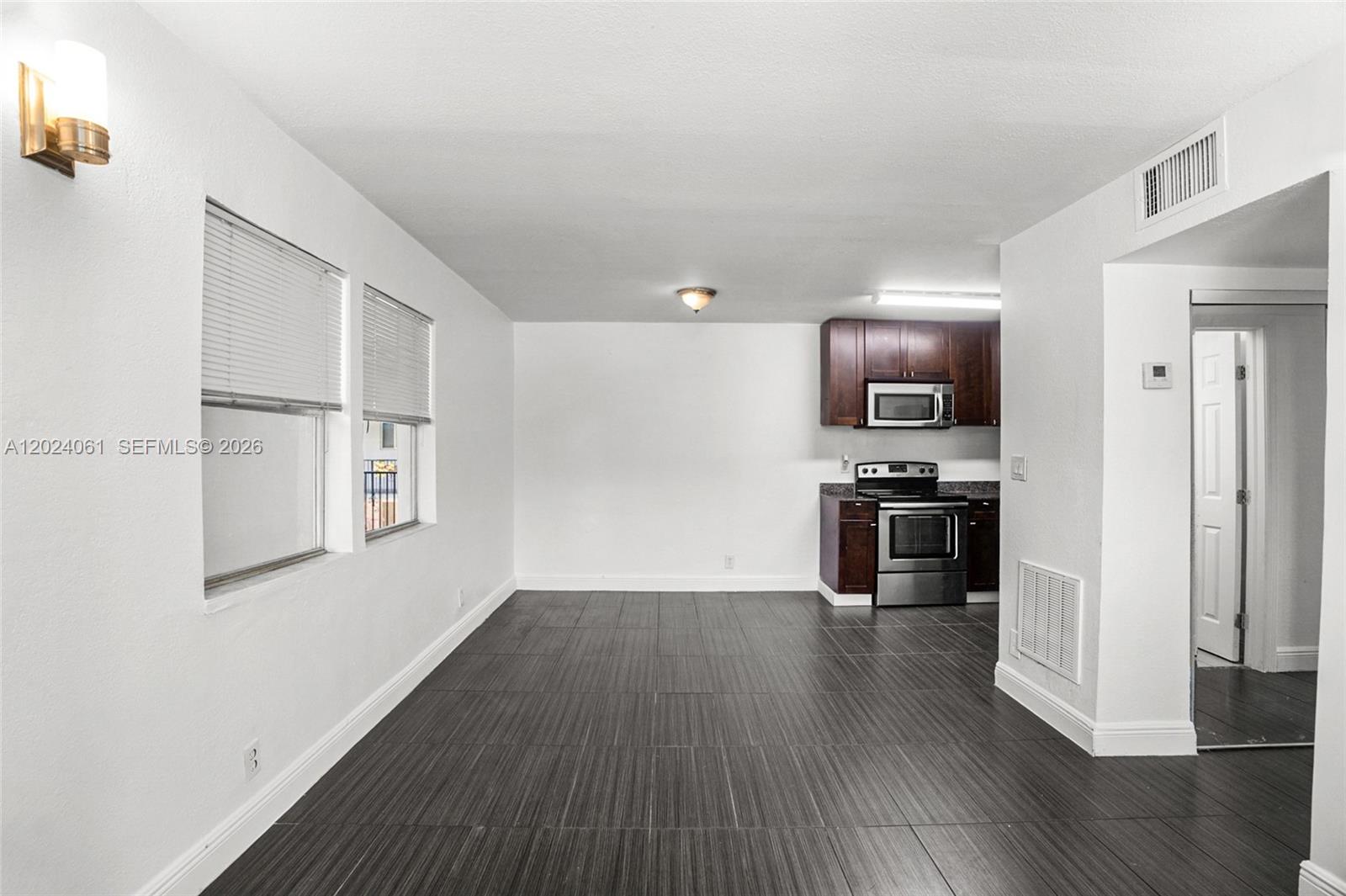 A kitchen with dark wood cabinets and stainless steel appliances opens into a dining area — 37 SW 14th St # 16, Dania Beach FL 33004, DANIA BEACH, FL