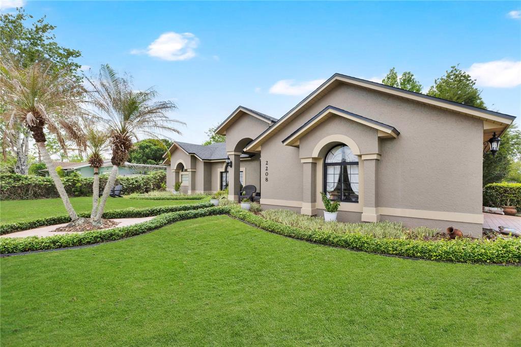 A single-story house with a tan stucco exterior, arched window, and a manicured front lawn — 2208 ARCHER BOULEVARD, ORLANDO, FL