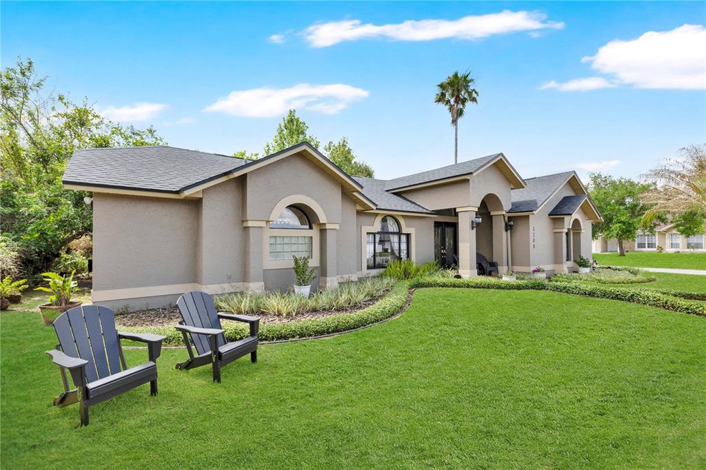 A single-story house with a tan stucco exterior, arched windows, and a manicured front lawn — 2208 ARCHER BOULEVARD, ORLANDO, FL
