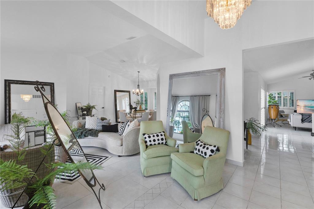 A bright living room features light green armchairs, a curved sofa, and large floor mirrors — 2208 ARCHER BOULEVARD, ORLANDO, FL