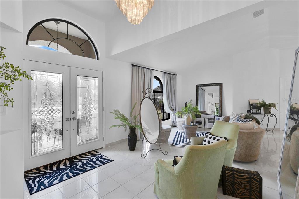 A bright, tiled entryway features double glass doors, a chandelier, and a seating area — 2208 ARCHER BOULEVARD, ORLANDO, FL